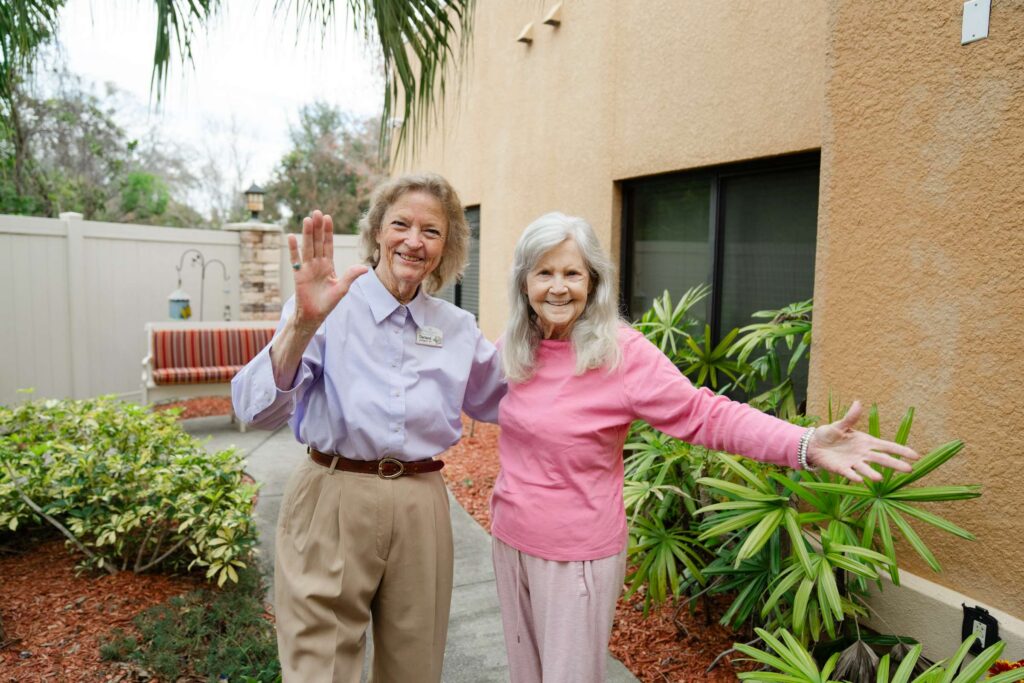 AgeWell team member enjoys weather in outdoor courtyard with senior resident